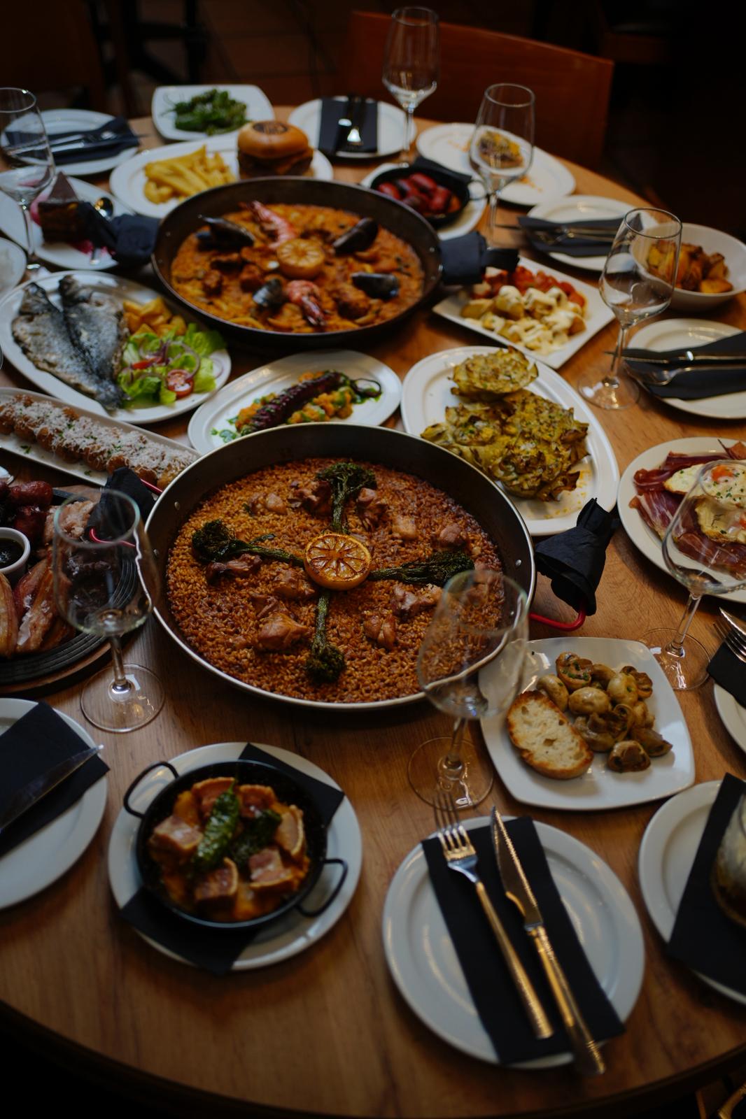 Mesa con paella y platos a la brasa en Cavacarbon, Cava Baja 8, Madrid