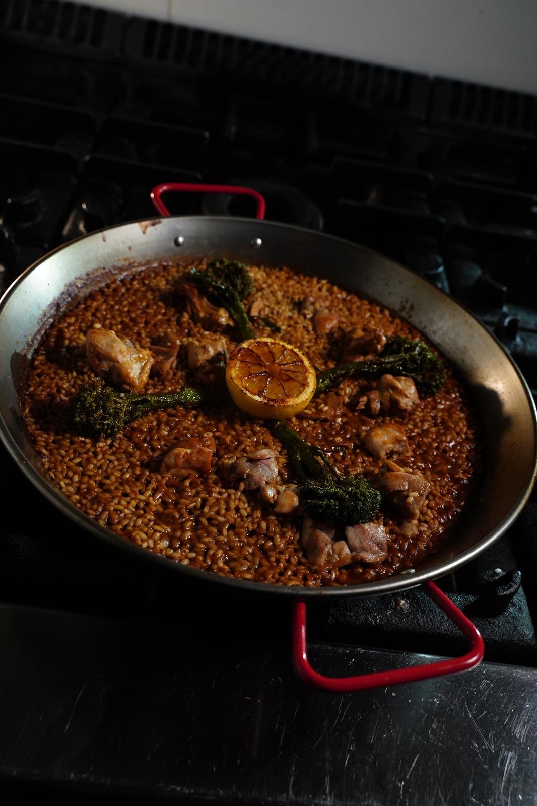 Paella mixta al carbón terminándose al fuego en Cavacarbon, La Latina, Madrid